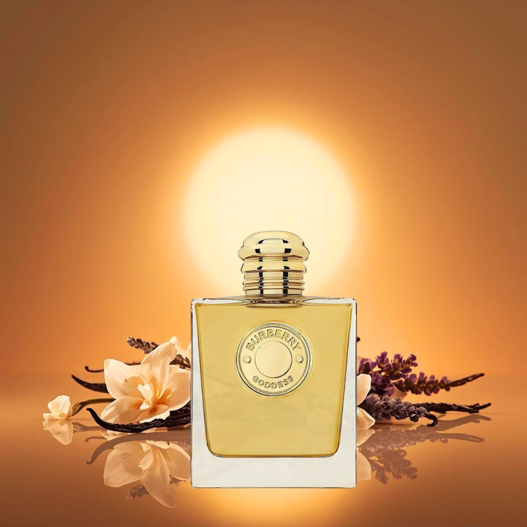 Flakon perfum Burberry Goddess Intense stoi pionowo pośrodku kadru na złocistym tle. Wokół widać laski wanilii, lawendę i miękkie bursztynowe światło, które podkreśla ciepło i elegancję zapachu.