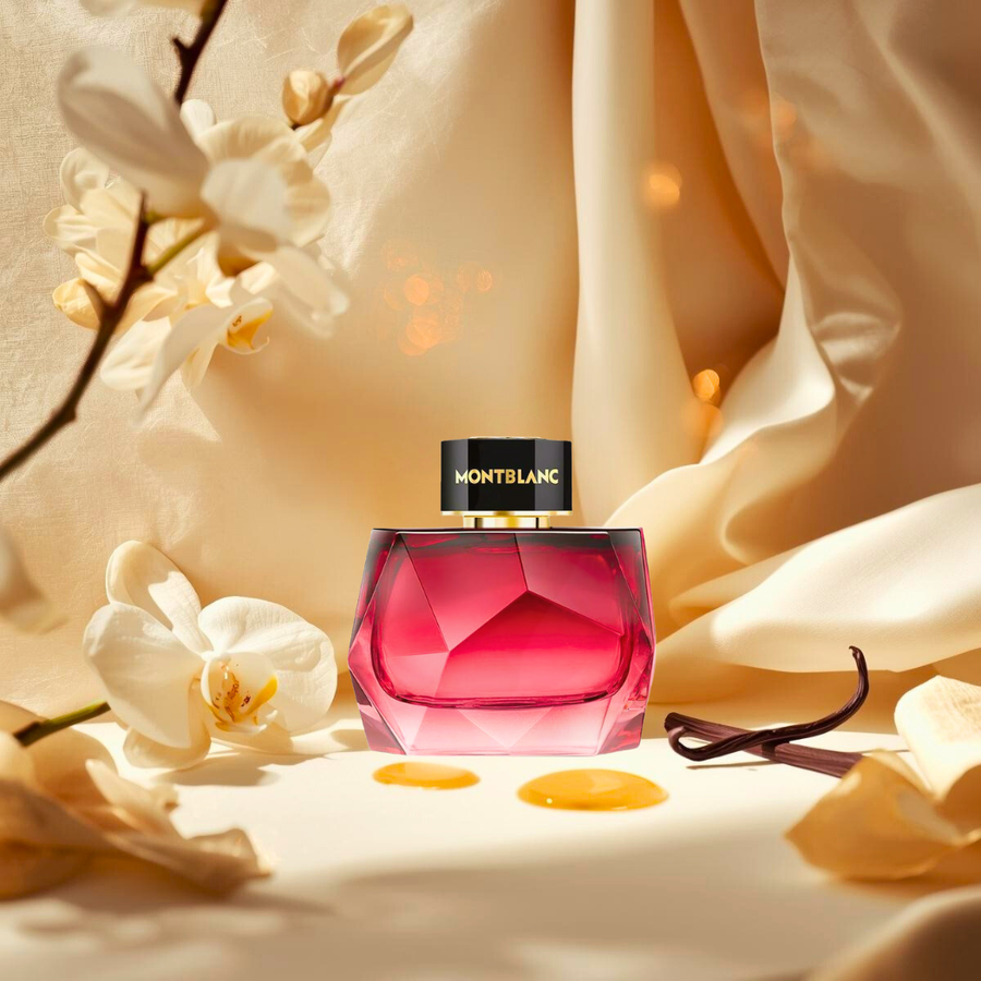 Elegancki flakon perfum Montblanc Signature Elixir stoi na kremowym tle w otoczeniu płatków orchidei, lasek wanilii i bursztynowych refleksów światła, symbolizujących ciepło i kobiecość zapachu.